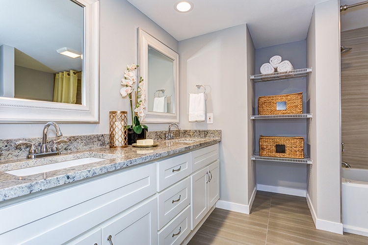 Elegant bathroom with long white vanity cabinet, granite counter top, two sinks and built in shelves.